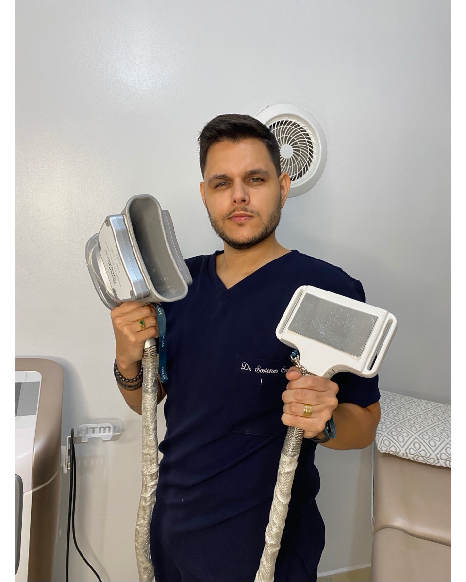 Sóstenes de uniforme da clínica segurando as ponteiras dos equipamentos de estética